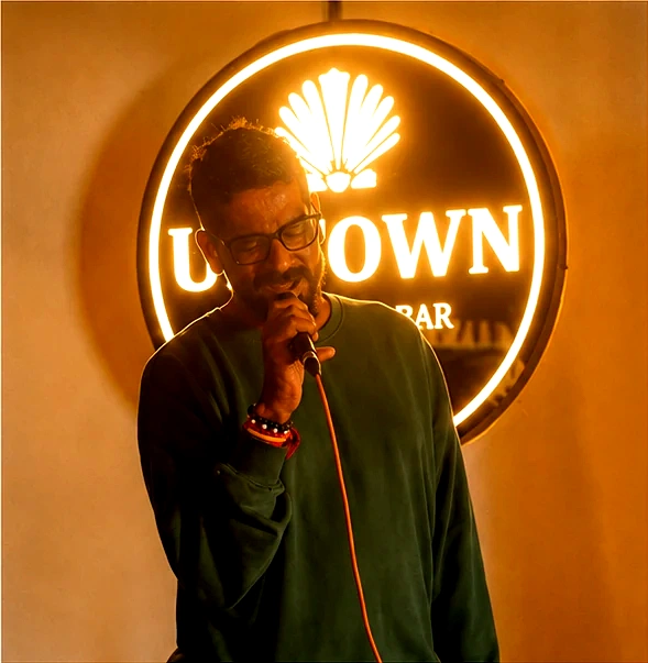 A singer mid-set under the lit Uptown sign